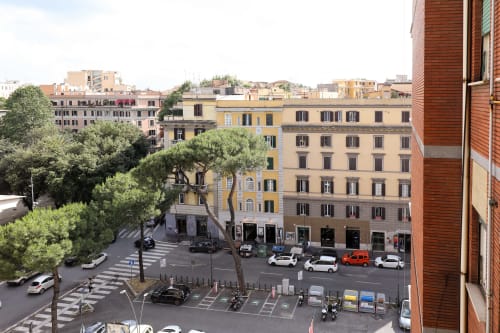 Vista di Roma dall'appartamento Re di Roma: palazzi europei, strada, alberi e auto parcheggiate