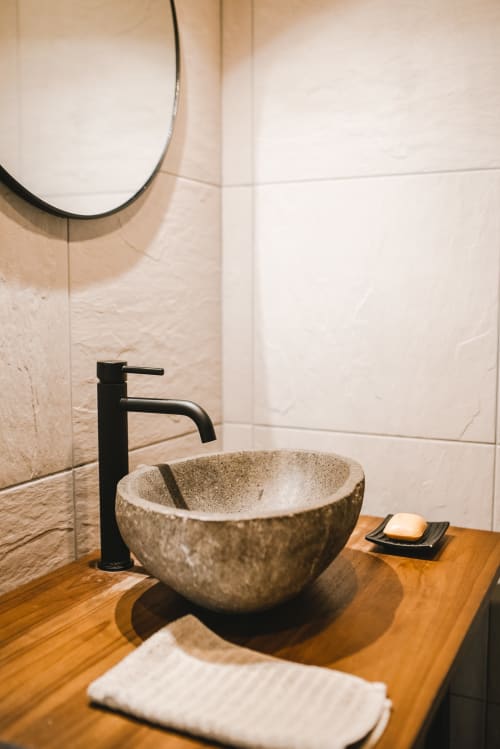Lavabo moderne avec vasque en pierre, robinetterie noire et comptoir en bois à l'hôtel ART DE VOYAGER à Étretat