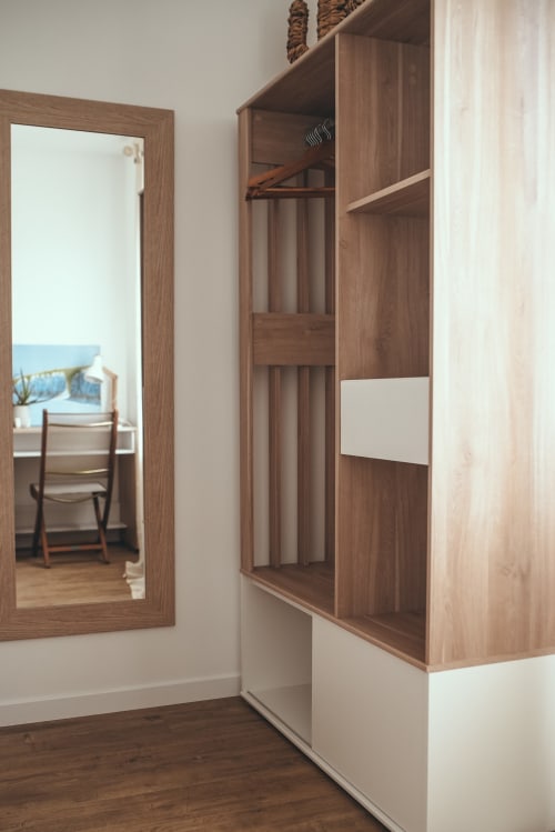 Armoire moderne en bois avec base blanche dans la chambre de l'hôtel Étretat, miroir reflétant la vue côtière