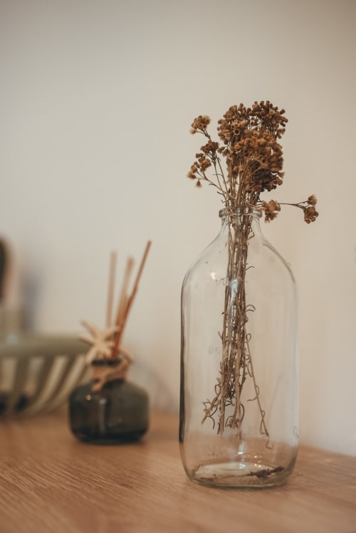 Fleurs séchées dans une bouteille en verre transparent sur une surface en bois à l'hôtel Art de Voyager à Étretat, France