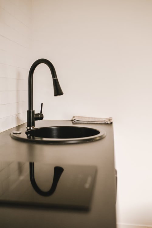 Lavabo noir moderne et robinetterie avec serviettes pliées à l'hôtel ART DE VOYAGER à Étretat