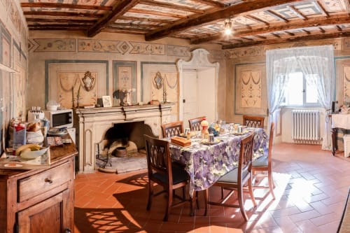 Sala da pranzo rustica a Villa Pandolfi Elmi a Spello con pareti affrescate, camino e travi di legno