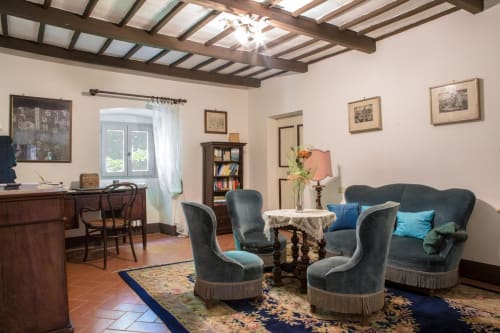 Elegante soggiorno di Villa Pandolfi Elmi a Spello con poltrone in velluto blu, arredi tradizionali e travi in legno a vista