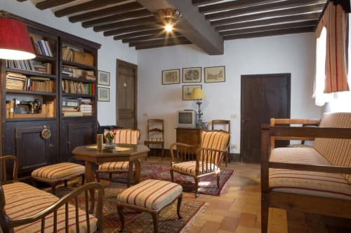 Elegante soggiorno di Villa Pandolfi Elmi a Spello con sedie rigate, travi in legno e librerie