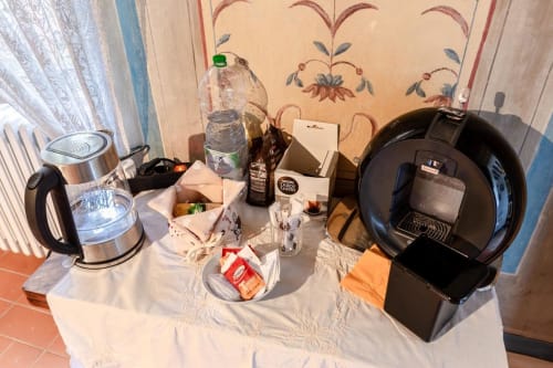 Accoglienza presso Villa Pandolfi Elmi a Spello con bollitore, caffettiera, bottiglia d'acqua e rinfreschi su bianco