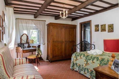 Camera da letto rustica a Villa Pandolfi Elmi a Spello con travi in legno, pavimenti in cotto e mobili antichi