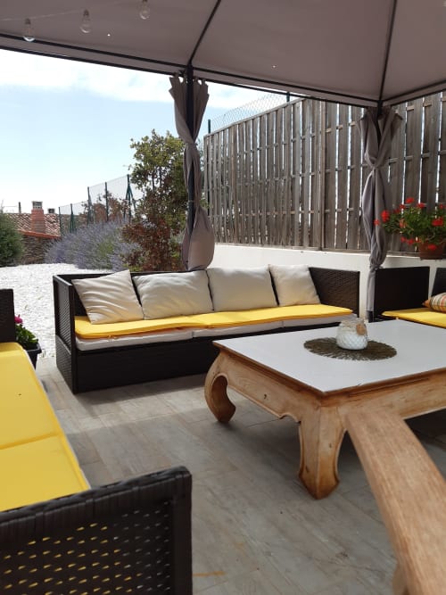 Coin repas extérieur du gîte Casa Rural La Perla avec sièges aux coussins jaunes, table en bois et parasols