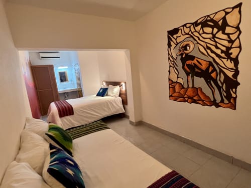 Camas gemelas en habitación del Hotel Boutique BajaReal, La Paz, con arte decorativo de fauna silvestre y mobiliario moderno