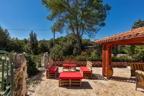 Terrazza esterna di Villa Margherita con sedute in pallet rossi, pergolato arancione e vista sulla campagna di Santeramo