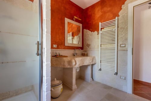 Bagno moderno a Villa Margherita con pareti arancioni vivaci, lavabo in marmo, scaldasalviette e pavimentazione in cotto