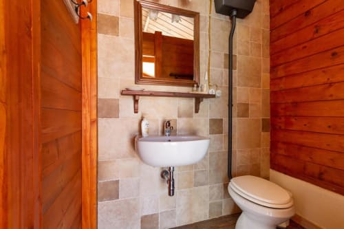 Bagno rustico alla Villa Margherita con pareti in legno, accenti in piastrelle, lavandino bianco, WC e specchio a Santeramo in Colle