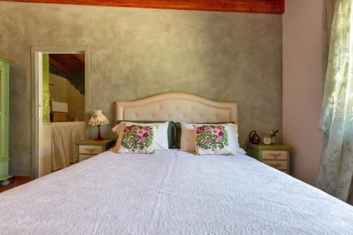 Camera padronale con testata letto in velluto pesca, cuscini floreali e vista sul lago a Villa Margherita, Santeramo in Colle