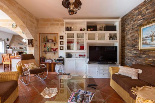 Soggiorno accogliente di Villa Margherita con pavimenti in terracotta, arredi bianchi, sedute marroni e parete in mattoni a vista
