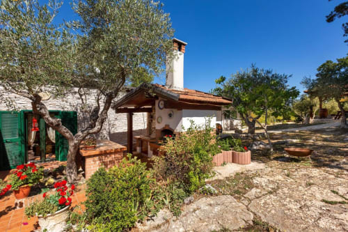 Cortile di Villa Margherita a Santeramo in Colle con ulivi, fiori rossi e architettura italiana tradizionale