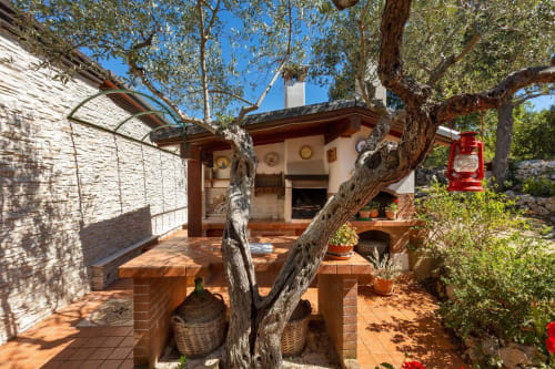 Affascinante cortile di Villa Margherita con piastrelle in terracotta, antichi ulivi e architettura in pietra rustica a Santeramo