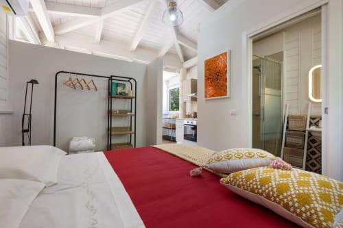 Camera luminosa a Villa Margherita con passatoia rossa, cuscini decorativi, scaffalature metalliche e bagno ensuite a Santeramo