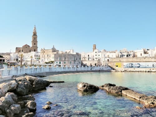 Petit village côtier méditerranéen avec église historique et bâtiments blancs au bord de l'eau à Santeramo in Colle, Italie