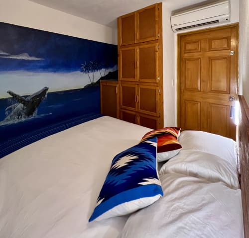Dormitorio con temática marina en BajaReal Hotel Boutique de La Paz con mural de ballena, muebles de madera y ropa de cama colorida