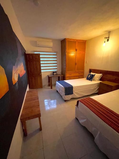 Habitación espaciosa del Hotel Boutique BajaReal en La Paz con dos camas, muebles de madera e iluminación cálida