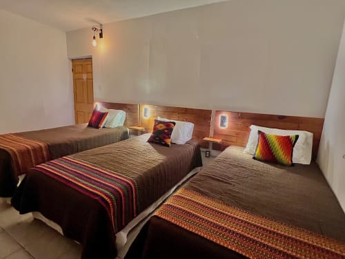 Habitación del Hotel Boutique BajaReal en La Paz con tres camas, almohadas a rayas coloridas, cabeceros de madera e iluminación cálida