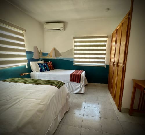 Habitación moderna del Hotel Boutique BajaReal en La Paz con dos camas, detalles en turquesa y persianas estriadas