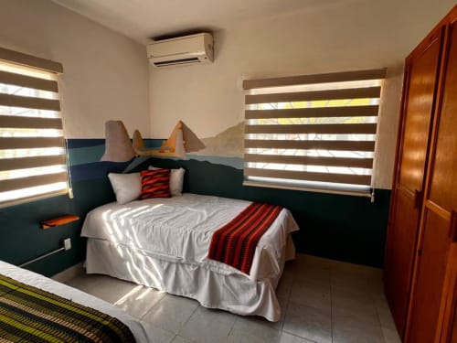 Habitación moderna del BajaReal Hotel Boutique en La Paz con mural de montaña, ropa de cama a rayas y ventanales contemporáneos