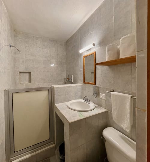 Cuarto de baño moderno en BajaReal Hotel Boutique de La Paz con pisos de mármol, lavabo redondo y cabina de ducha