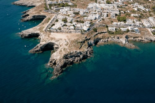 Vista aerea di Panoramici Monolocali a Leuca - eleganti costruzioni bianche sulla costa rocciosa con acque turchesi