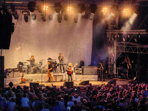 Live band performing on stage with crowd at Les Chalets Du Lac De Montréjeau venue in Clarac, France