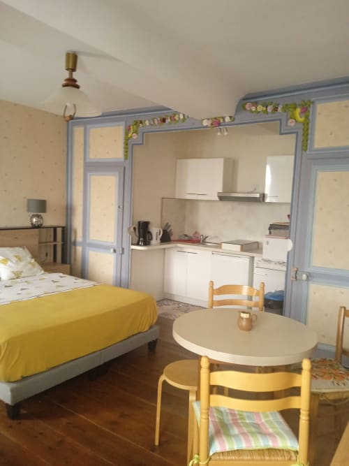 Chambre double standard aux Clématites en Cotentin avec literie jaune, table à manger, kitchenette et portes à encadrements bleus