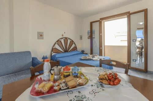Appartamento con vista sul mare presso Panoramici Monolocali a Leuca, con letto blu, tavolo da colazione preparato e balcone
