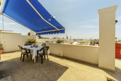 Terrazza panoramica a Panoramici Monolocali a Leuca con tenda blu, tavolo da pranzo e vista mare