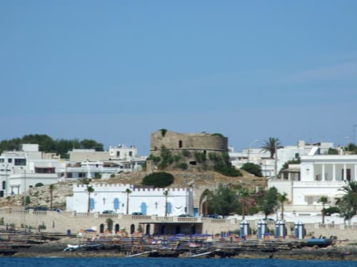 Monolocali panoramici dell'hotel di Leuca con torre storica e vista sul mare, edifici bianchi sotto cielo azzurro