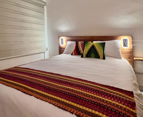 Recámara moderna en BajaReal Hotel Boutique de La Paz con cabecera de madera, iluminación ambiental y textiles tejidos coloridos