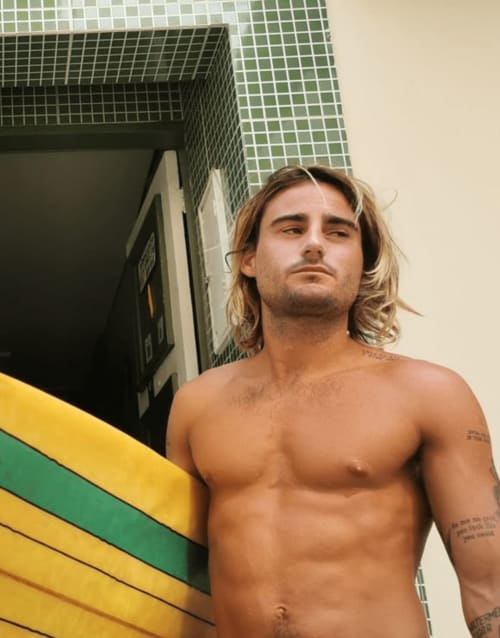 Homem sem camisa na Pousada New Ipanema Rio de Janeiro com painel geométrico colorido ao fundo