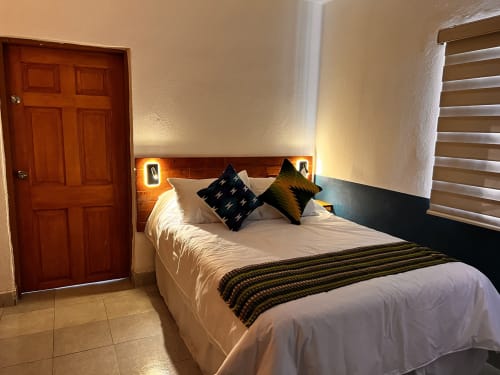 Moderna habitación del Hotel Boutique BajaReal en La Paz con ropa de cama blanca, almohadas decorativas, cabecero de madera y ambiente acogedor