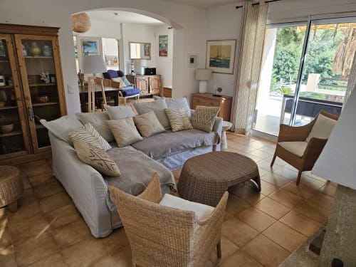 Bright living room at Villa Sigahi in La Croix Valmer with comfortable seating, rattan chairs, and pool view through glass