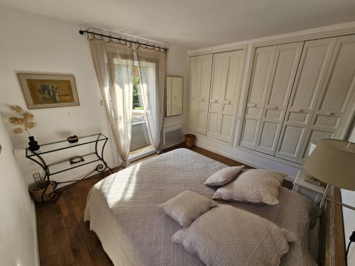 Elegant bedroom at Villa Sigahi in La Croix Valmer with queen bed, built-in wardrobes, and glass doors opening to pool view