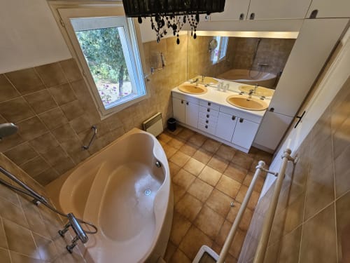 Spacious bathroom at Villa Sigahi with freestanding tub, double vanity, and garden view in La Croix Valmer