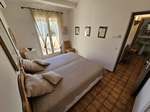 Bright bedroom at Villa Sigahi with double bed, terracotta tiles, and French doors opening to pool view in La Croix Valmer
