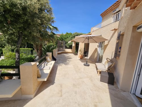 Sunny terrace at Villa Sigahi in La Croix Valmer with patio furniture, umbrellas, and lush greenery