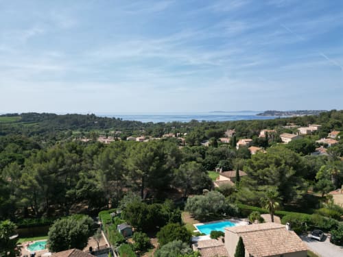 Vue aérienne de la Villa Sigahi surplombant La Croix Valmer, la Méditerranée, les piscines et le village côtier niché dans les pins