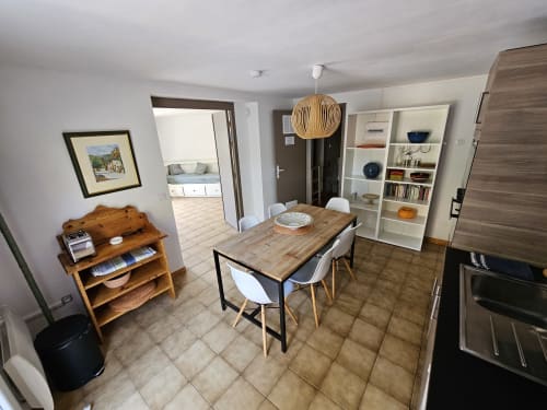 Salle à manger de l'appartement Sigahi à Villa Sigahi à La Croix Valmer avec table en bois, étagères blanches et accès à la cuisine