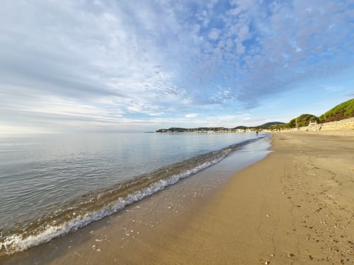 Sandy beach at Villa Sigahi with calm Mediterranean waters and coastal village in La Croix Valmer