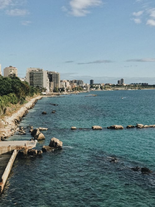 Vista costiera di CorteLirice Paradiso con acque turchesi del Mediterraneo, riva rocciosa ed edifici sul mare in Italia