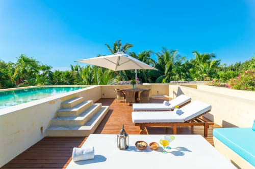 Terraza de villa de lujo en Tulum con piscina, tumbonas, comedor, palmeras y vistas al mar