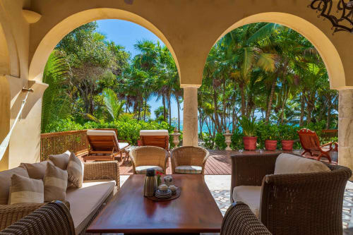Lujoso patio frente al mar de la villa Hacienda Chekul en Tulum con asientos de mimbre, vistas al océano y jardín tropical