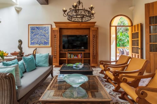 Sala de estar de la villa Hacienda Chekul en Tulum con acentos turquesas, muebles de madera, televisor y puerta arqueada hacia la terraza