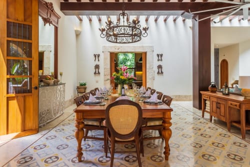 Elegante comedor en la villa Hacienda Chekul, Tulum con mesa de madera, araña ornamental y decoración de estilo mediterráneo