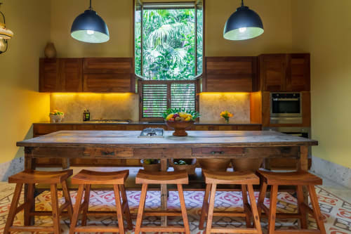 Cocina y comedor moderno en villa Hacienda Chekul, Tulum, con isla de madera, lámparas colgantes y vistas tropicales